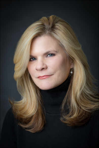 Professional headshot of blonde woman in black turtleneck smiling confidently against dark background new jersey.