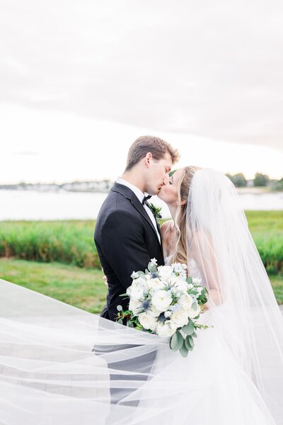 Bride and groom kissing in front of beach grasses during their Danversport wedding in Danvers, MA