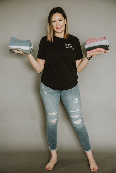 woman holding a stack of t-shirts
