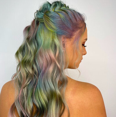 Image of client with hair that has been dyed a blend of greens, pinks, and blues.
