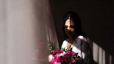 Bride with her florals standing next to the window.