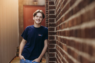teen-boy-leaning-on-brick-wall