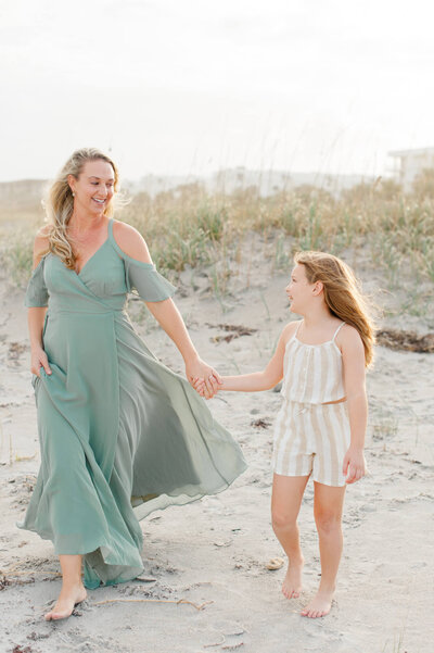 Mom and daughter holding hands and walking along the beach