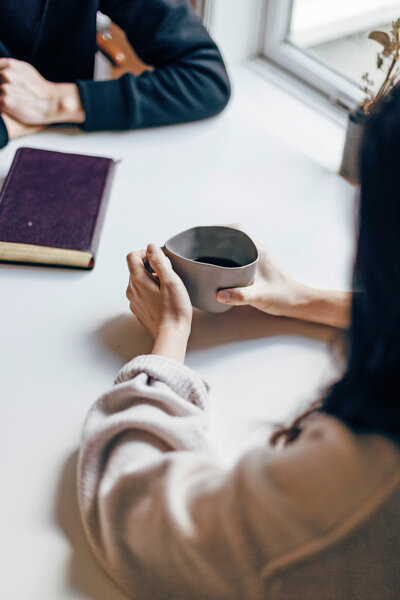 Two people doing a therapy session with coffee and books at the table
