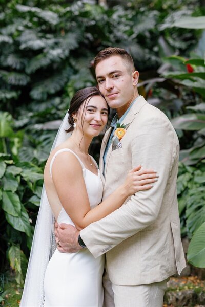 A newlywed couple with their arms around each other and smiling 