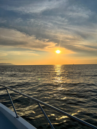 A picturesque sunset over the ocean viewed from a boat, capturing the romantic essence of a destination wedding.