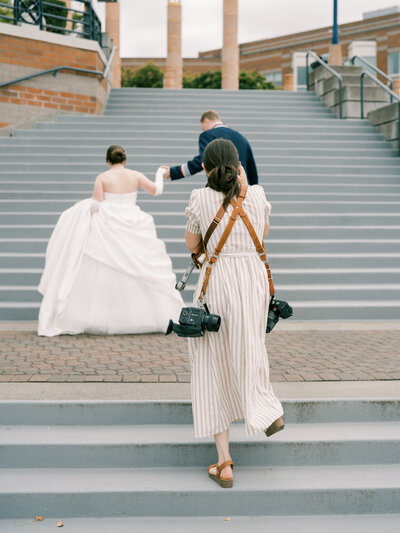 Kirkland wedding photographer in action walking down stairs with two cameras on holdfast straps
