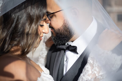 Elopement Wedding Packages Rhode Island | Kelsey Sheehan Photography Timeless Rhode Island Weddings | A bride and groom share an intimate moment under a veil, their foreheads touching. The mood is tender and romantic, with soft lighting enhancing the scene.