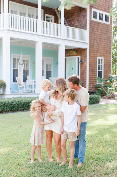 Beautiful family standing in front of their Merritt Island home while their photographer captures them sharing a candid moment.