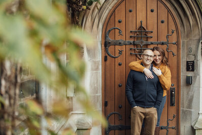Princeton University | Couple smiling during engagement photo by doorway | New Jersey