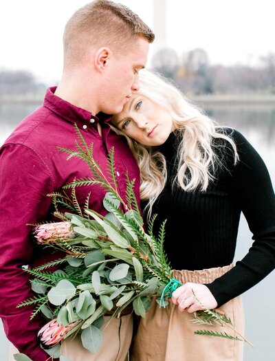 Engaged couple standing together holding flowers