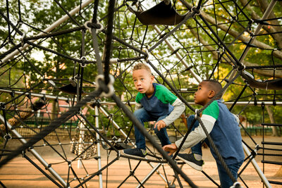 Brothers climbing a playground structure in Boston