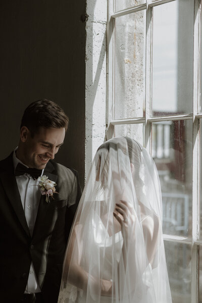 Artistic modern editorial wedding portrait of bride and groom gazing out loft window in Toronto — Acrewood photography