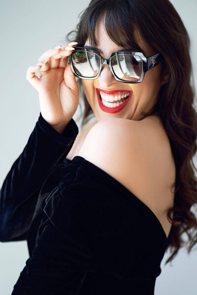 femme souriant avec des grandes lunettes de soleil et du rouge à lèvres
