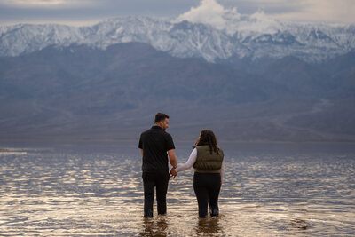 A couple holding hands and walking in shallow water