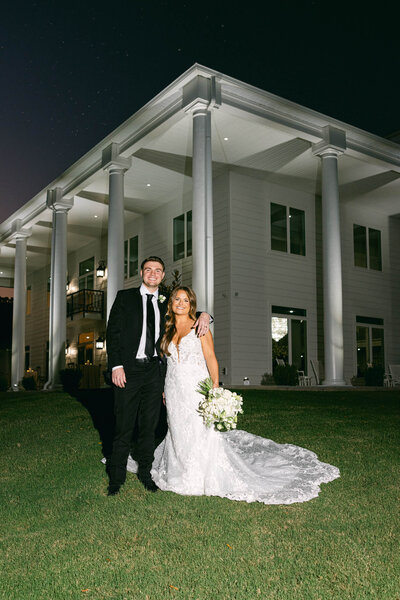 a wedding photo of the couple smiling for the camera in front of  Legacy acres in Arkansas