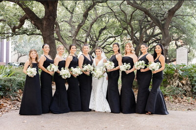 bride standing with bridesmaids in black dresses