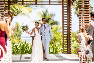 a couple having a luxury destination wedding gazebo with tropical florals and views of the ocean