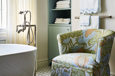 A Boston kitchen and bath designer transforms a Milton primary bathroom with a custom upholstered chair, blending luxury and function in a partial home renovation.