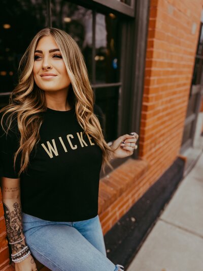 Kate Boggs in front of a brick wall and window.