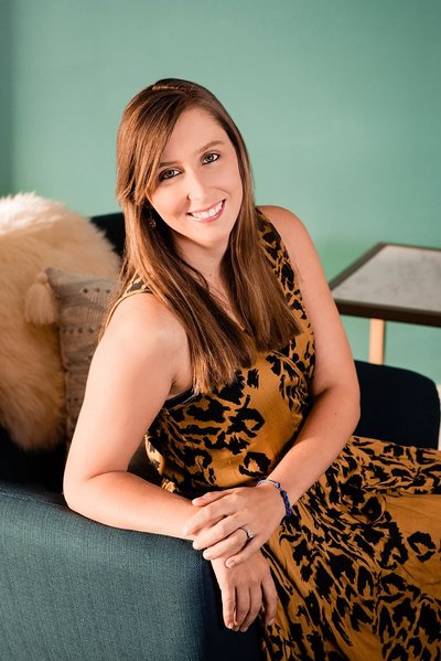 Headshot photo for Murfreesboro small business owner dressed in a gold and black full length dress and sitting in a chair