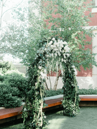 A wedding magazine surrounded by a Canon camera, red and pink cloth, flowers, leaves and a wedding ring