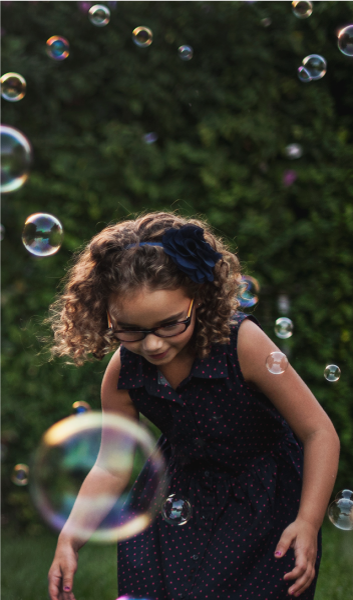 child playing in bubbles at the park