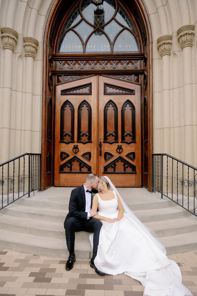 bride and groom kissing on the steps of Basilica of the Sacred Heart