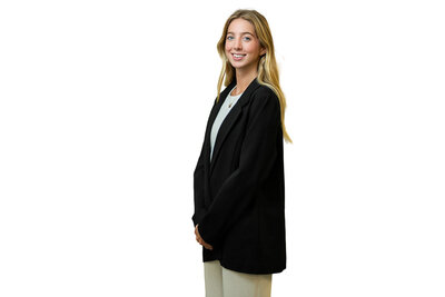 Professional headshot of woman in green dress smiling warmly against soft blurred background new york.