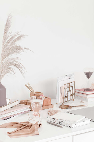Styled home office desk with neutral stationery, pampas grass, and organized folders, representing HoneyBook backend cleanup and sustainable workflows for wedding photographers.