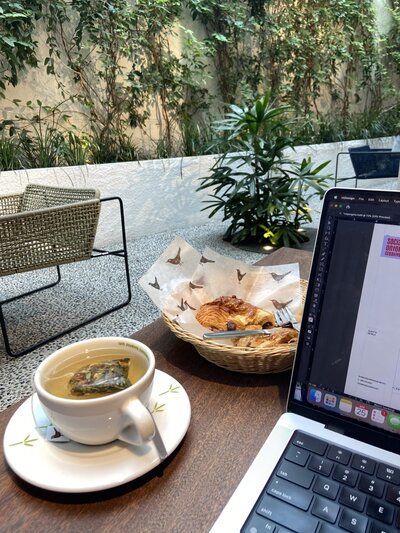 tea and croissant sitting next to a computer in a cafe