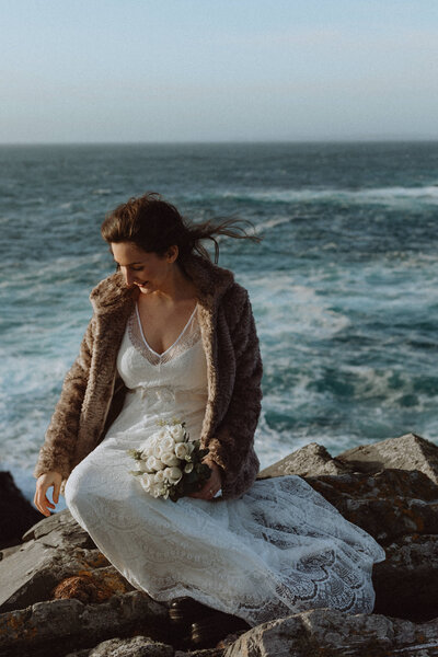 bride and groom stand in the wind on a cliff