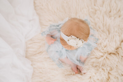 Six month old baby boy smiling at the camera, dressed in white