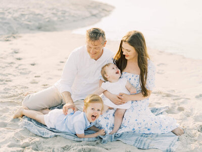 family of five pose for a photo on the beach in blue and white by carrie pellerin