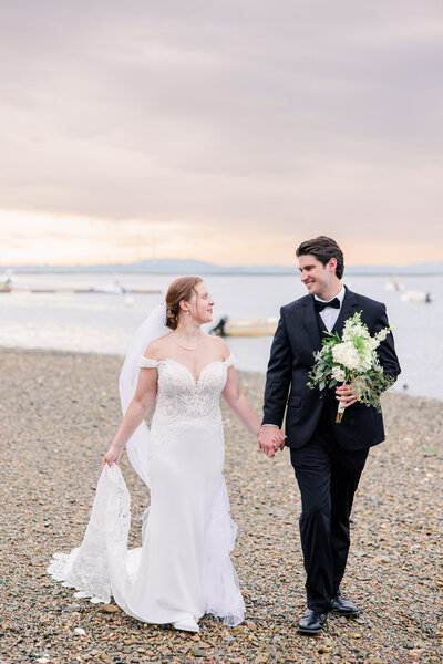 Bride and groom holding hands and walking on the beach