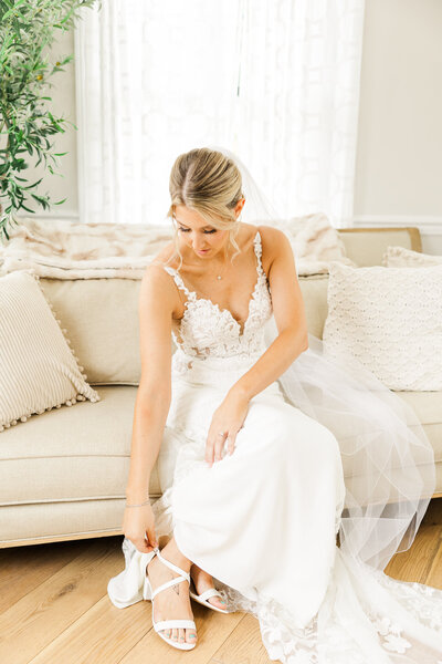 Bride in dress in bridal suite putting on shoes in Sky View Golf Club- Sparta NJ