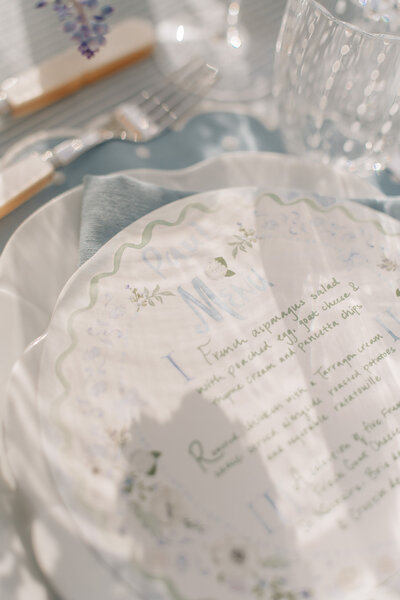 Hand-painted round wedding menus with squiggle and scallop details, floral motifs and hand-brushed lettering