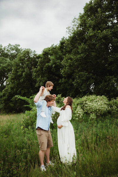 A family of three plays while the son is up on dads shoulders during their family photos session in Madison WI.