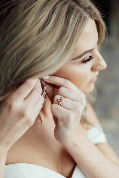 Close-up of the bride adjusting her earrings.
