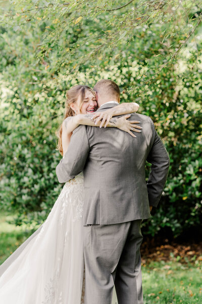 bride and groom embracing surrounded by large bushes during wedding photo session in upstate ny