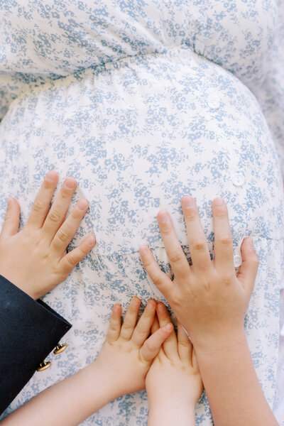 siblings hold hands on baby bump during lookout mountain maternity photography session