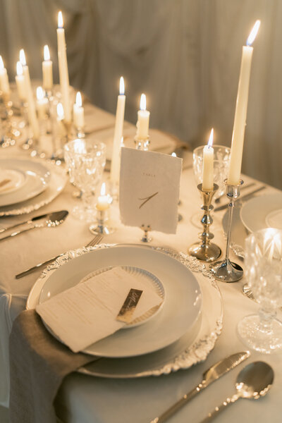 Fine art wedding reception table with luxury menus, place cards, table number and soft romantic candle light
