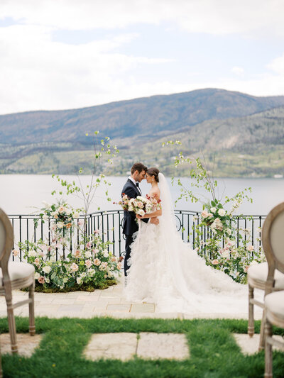 A bride in her wedding gown holds flowers and looks out of the window.