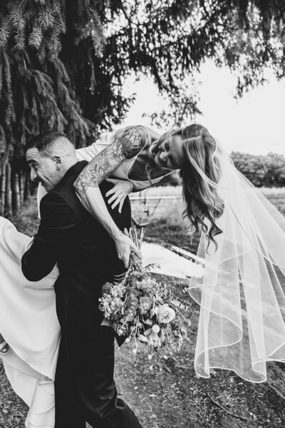 laughing newlyweds carrying bride