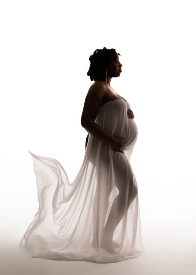 African American Maternity portrait  with flowing fabric on white backdrop