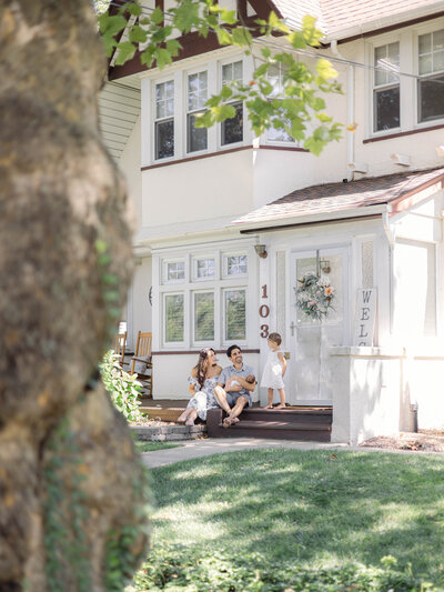 Family laughing together outside their family home during a newborn session.