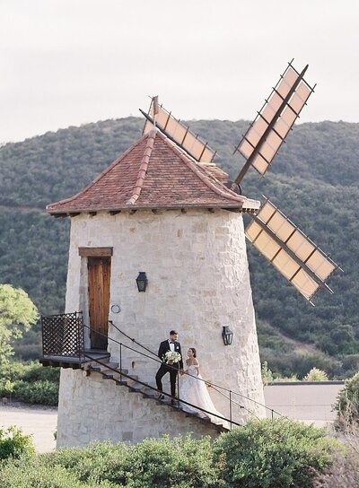 bride and groom on French windmill at cal a vie wedding - Jacqueline Benét