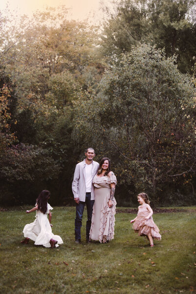 Family Portrait with happy parents standing together with their daughters playing ring around the rosey around them