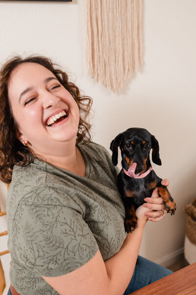 woman laughing while holding a wiener dog