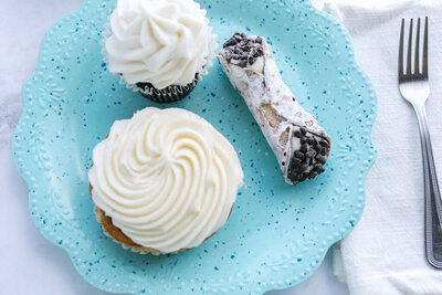 cinnamon roll, cupcake and cannoli on blue plate
